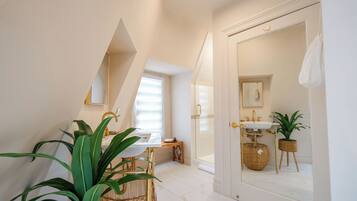 A modern bathroom with a large mirror, a sink, and a window.