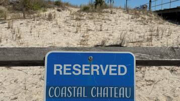 A blue sign with white text stating 'RESERVED COASTAL CHATEAU' on a wooden fence.