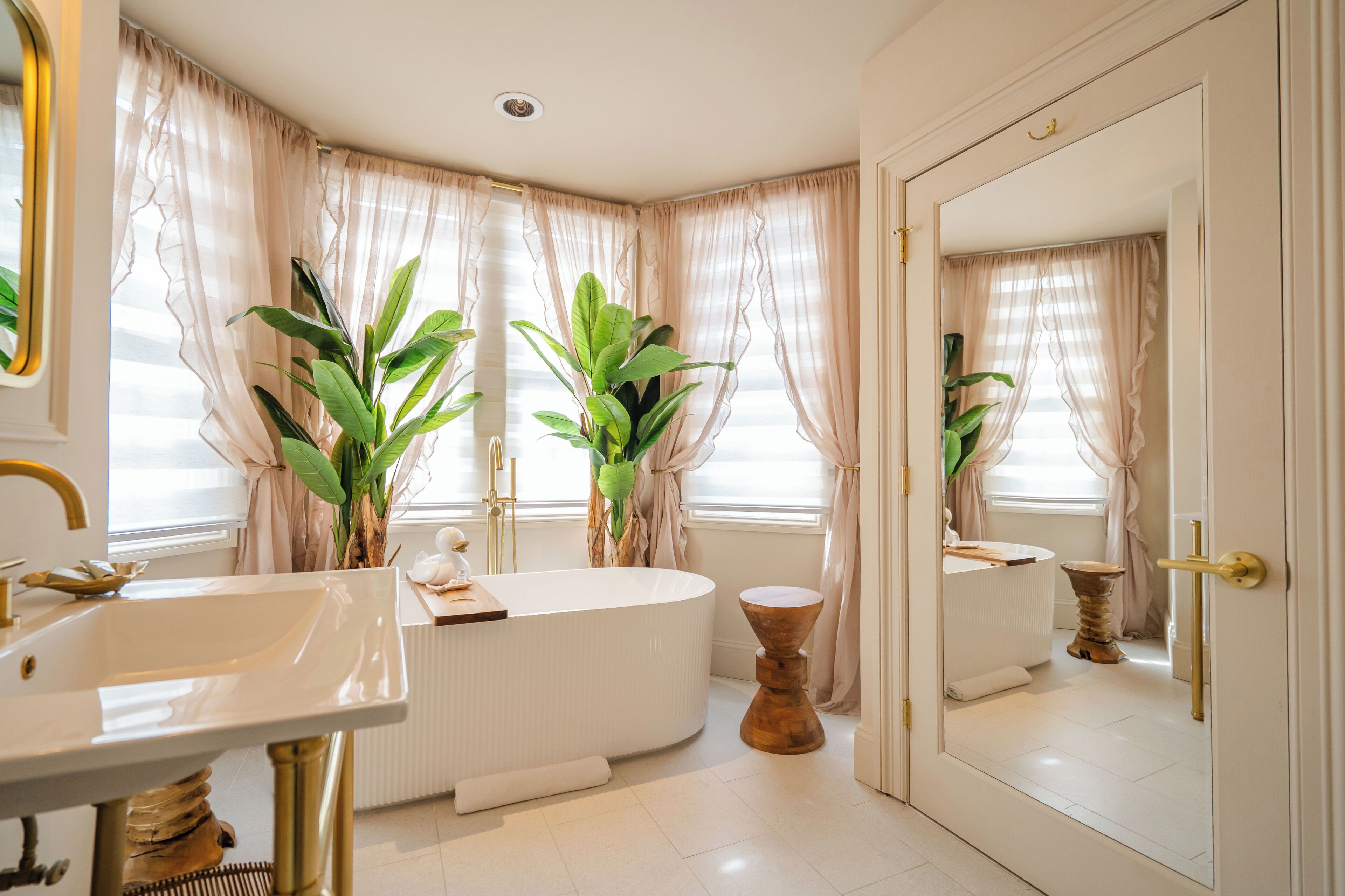 Un baño con bañera, lavabo y plantas grandes en macetas.