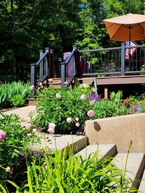 A garden with a wooden deck, a metal railing, and a large umbrella.