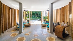 A spacious lobby with a modern design, featuring a central seating area with sofas and a coffee table, surrounded by wooden partitions and a patterned floor. - Private studio at Zen Space by Lofty (Kamala)