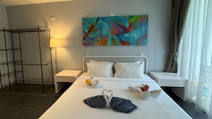 A hotel room with a large bed, a painting on the wall, a window with curtains, and a nightstand with a lamp. - Private studio at Zen Space by Lofty (Kamala)