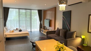 A modern hotel room with a bed, sofa, dining table, and a TV. - Private studio at Zen Space by Lofty (Kamala)