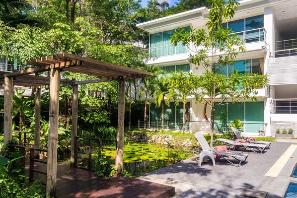 A modern building with a pool area, wooden pergola, and lounge chairs. - Private studio at Zen Space by Lofty (Kamala)