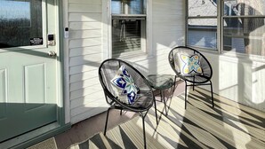 A porch with two black wireframe chairs, a star-shaped light fixture, and a door with a 'No Smoking' sign.