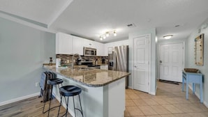 A modern kitchen with a central island, bar stools, a microwave, and a refrigerator. - Private Beach Access! Free Activities Fun Pass! Ciboney 4013! (Miramar Beach)