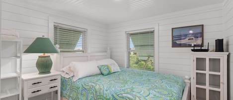 A bedroom with a bed, a nightstand, a lamp, a cabinet, and a window with blinds.