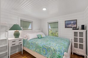 A bedroom with a bed, a nightstand, a lamp, a cabinet, and a window with blinds.