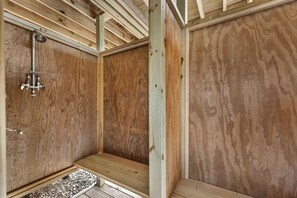 A wooden interior with a shower area, wooden flooring, and a visible metal pipe.