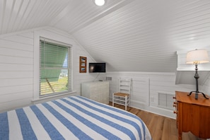 A bedroom with a bed, a television, a desk, and a chair.