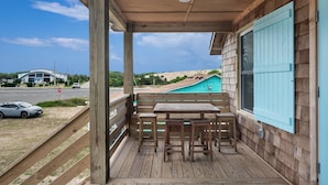 A wooden deck with a table and benches, overlooking a swimming pool and a road. - Nags Head 364: Pet Friendly, Newly Remodeled, Oceanside, Short Stays Anytime! (Nags Head)