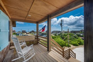 A wooden deck with a view of a beach and a flag.