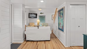 A white room with a bed, a lamp, and a painting on the wall. - Nags Head 364: Pet Friendly, Newly Remodeled, Oceanside, Short Stays Anytime! (Nags Head)