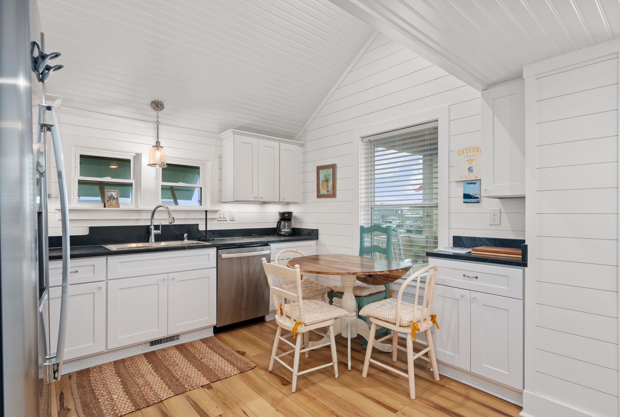 A kitchen with white cabinetry, a wooden dining table, and chairs.