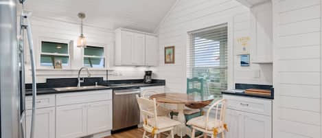 A kitchen with white cabinetry, a wooden dining table, and chairs.