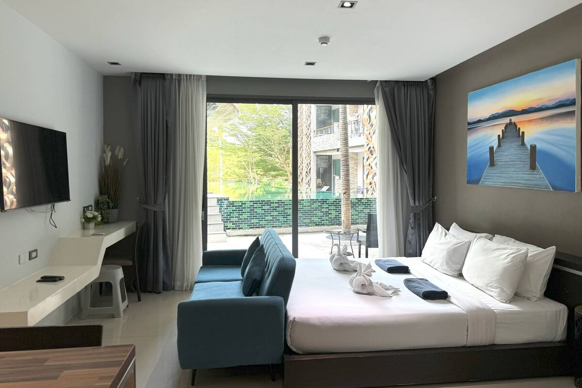 Ett modernt hotellrum med en stor säng, ett skrivbord, en soffa och en TV.