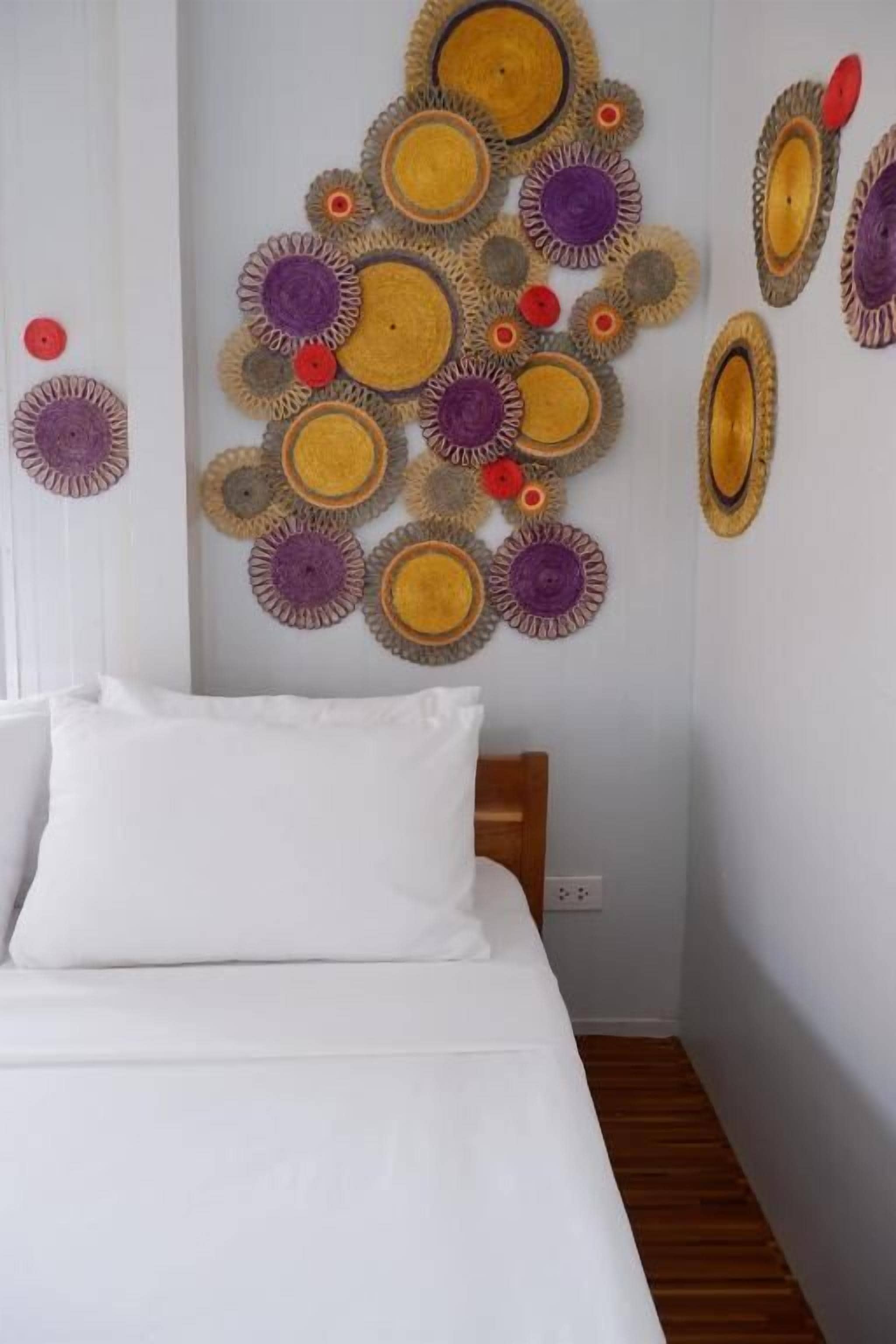 Un dormitorio con cama, ropa de cama blanca y una pared decorada con diseños circulares.