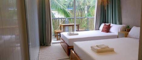 Habitación de hotel con dos camas, un balcón y vistas a palmeras, y una lámpara colgante.