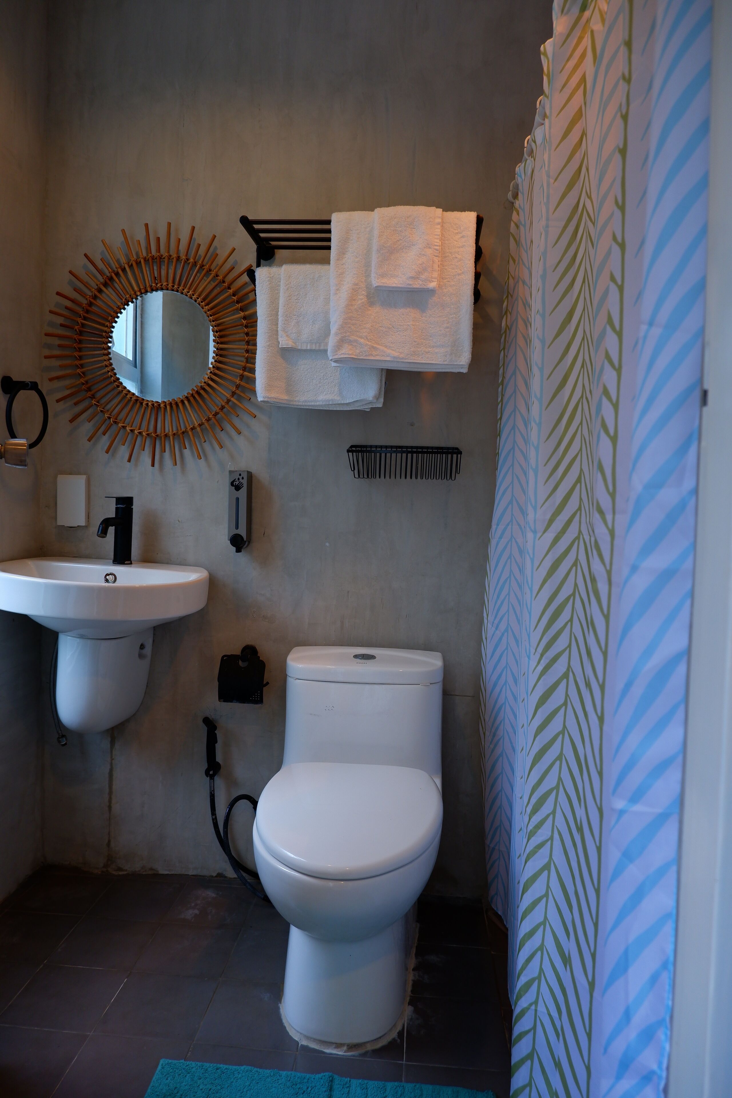 A bathroom with a sink, mirror, toilet, and shower curtain.