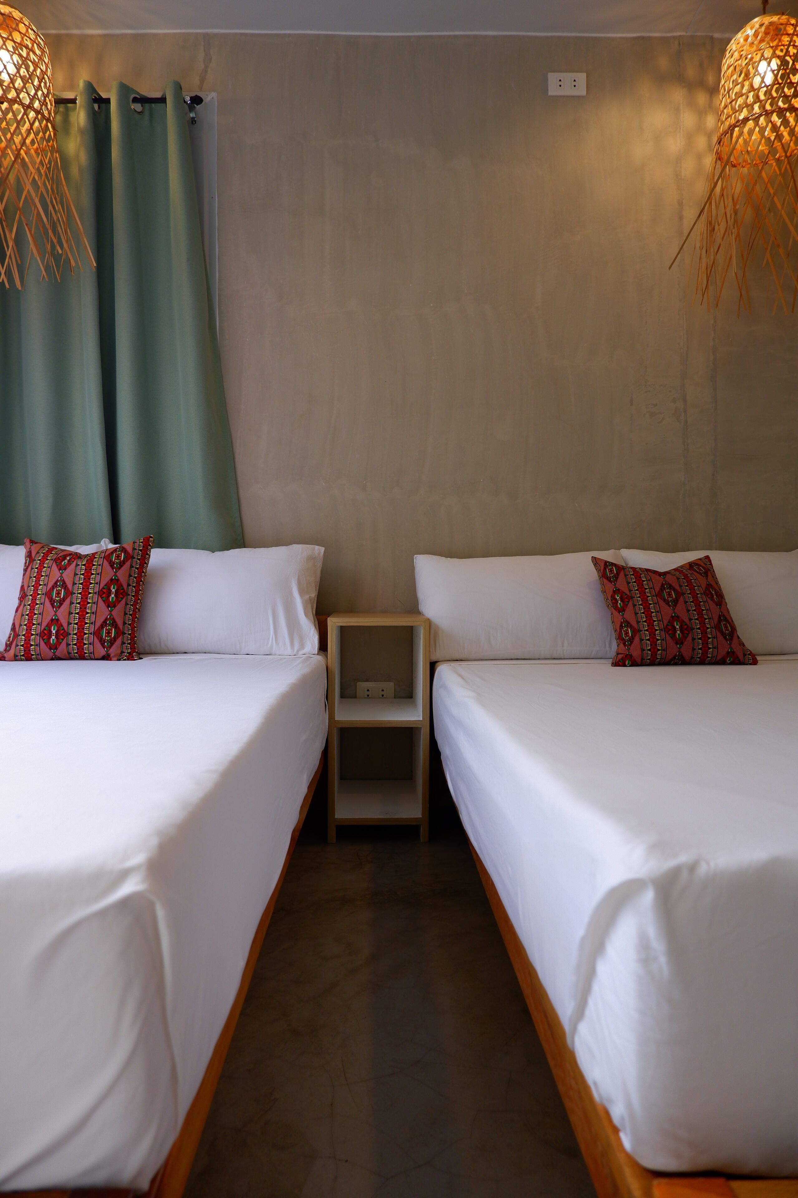 Habitación de hotel con dos camas individuales, una mesita de noche y una lámpara fijada a la pared.