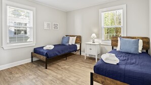 Une chambre avec deux lits, une table de chevet et une fenêtre avec des stores.