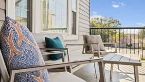Un balcon avec un canapé et des fauteuils, une table et une rambarde.