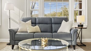 Un salon moderne avec un canapé gris, une table basse en verre et une lampe.