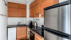 Una cocina compacta con armarios de madera, un refrigerador de acero inoxidable, lavavajillas y cafetera.