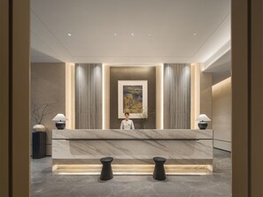 A modern reception desk with a marble top, flanked by two black stools, and a framed artwork above. - Somerset Pudong Riverside Shanghai (Shanghai)