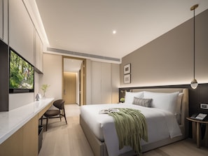 A modern hotel room with a large bed, a desk, and a television.