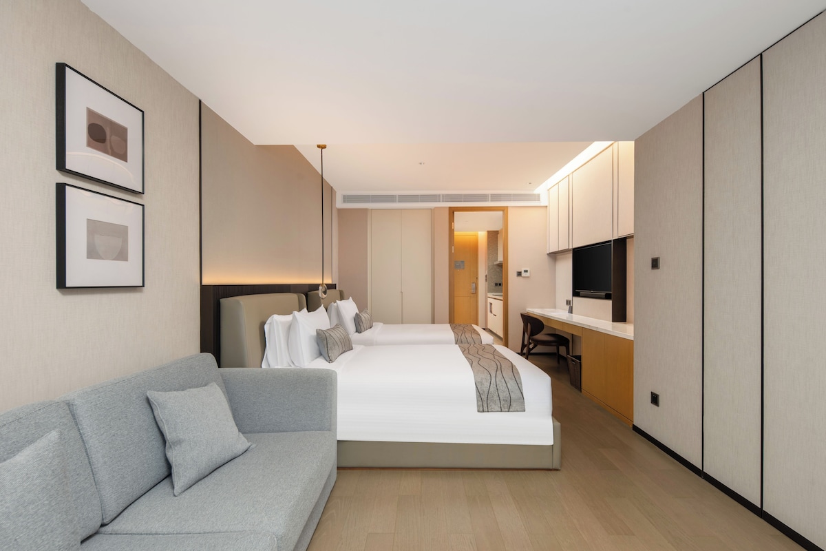 A hotel room with a bed, a sofa, a desk, a TV, and a wardrobe.