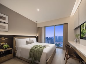 A modern hotel room with a large bed, a desk, and a city view.