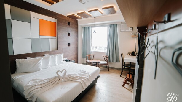Una habitación de hotel moderna con una cama grande, un área de comedor y vistas de la ciudad.