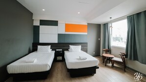 Una habitación de hotel con dos camas, una mesita y una silla.