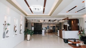 Un moderno vestíbulo de hotel con mostrador de recepción, zona de estar y plantas decorativas.