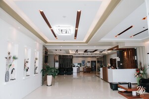 Un moderno vestíbulo de hotel con mostrador de recepción, zona de estar y plantas decorativas.