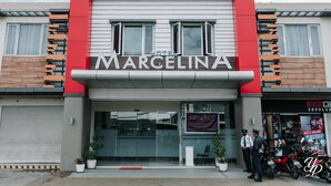 Un hotel llamado "Marcelina" con una fachada moderna, amplias ventanas y una pared de acento roja.