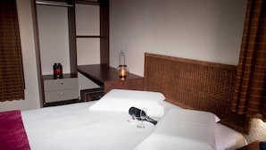 Quarto de hotel com cama, mesa de cabeceira, espelho, cômoda e abajur.