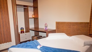 Quarto de hotel com uma cama, mesa de cabeceira, espelho e uma pequena estátua.