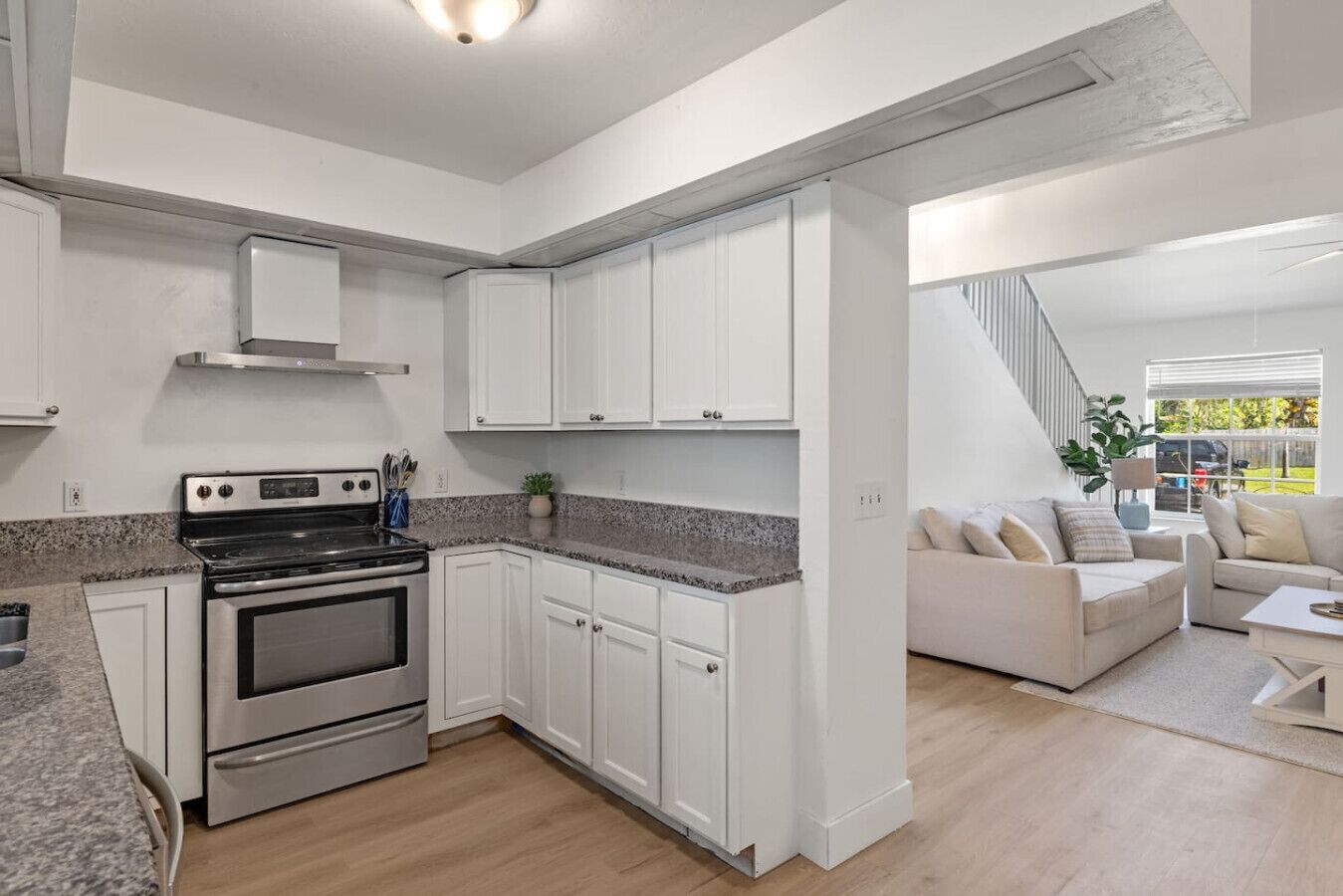 A modern kitchen with white cabinets, a stainless steel stove, and granite countertops.