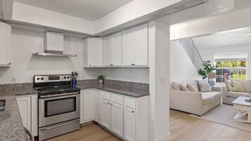 A modern kitchen with white cabinets, a stainless steel stove, and granite countertops.