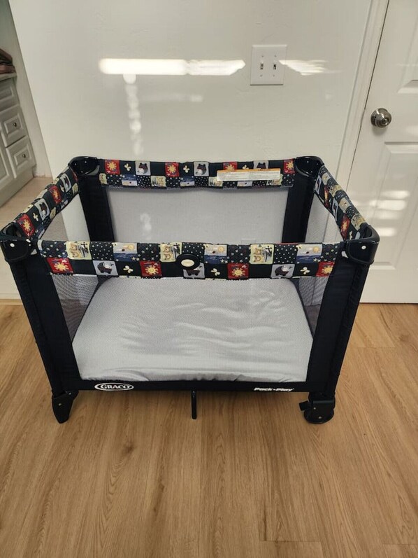 A Graco baby bouncer with a patterned fabric, placed on a wooden floor against a white door.