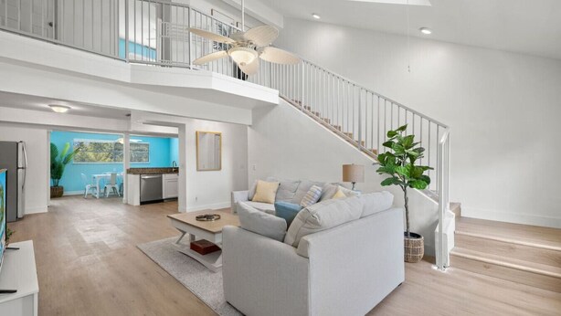 Un vaste espace de vie comprenant un canapé blanc, une table basse et un escalier menant à un niveau supérieur.