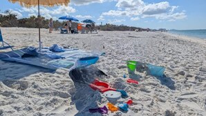 Une plage avec des parasols, des chaises longues et des jouets de plage.