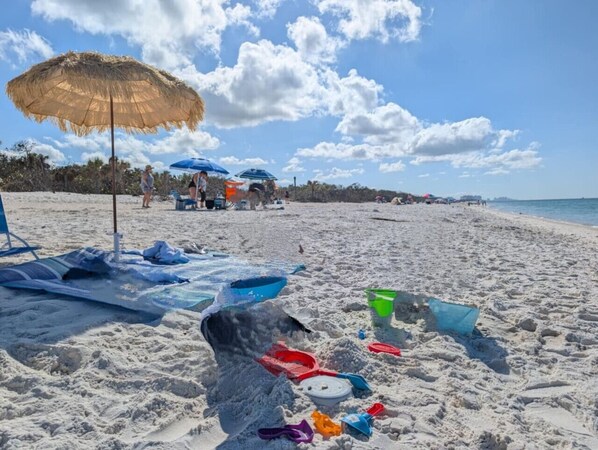 A beach with umbrellas, beach chairs, and sand toys.