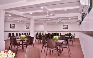 A conference room with tables and chairs, ceiling fans, and wall-mounted air conditioning units. - Hotel Pearls (Chhatrapati Sambhajinagar)