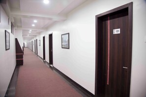 A long hallway with doors, each marked with a number, leading to individual rooms. - Hotel Pearls (Chhatrapati Sambhajinagar)