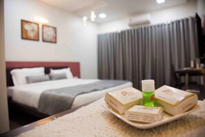 Een hotelkamer met een netjes opgemaakt bed, een dienblad met toiletartikelen en uitzicht op het interieur van de kamer.