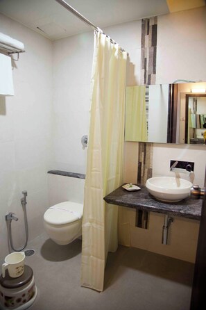 A bathroom with a toilet, sink, shower curtain, and a mirror. - Hotel Pearls (Chhatrapati Sambhajinagar)