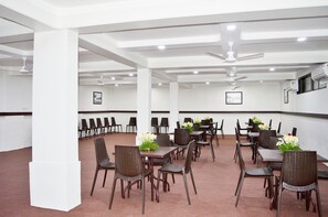 A conference room with tables and chairs, ceiling fans, and recessed lighting. - Hotel Pearls (Chhatrapati Sambhajinagar)